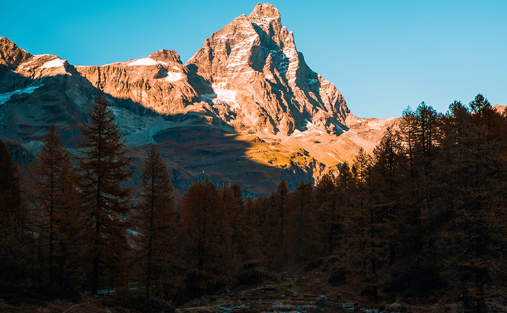 a tall, rocky mountain surrounded by trees overlooking a glassy lake